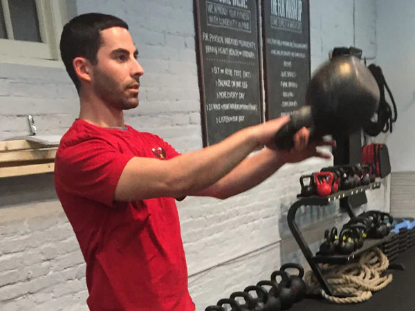 Ryan Jankowitz wechselt mühelos die Hände an der Spitze eines einarmigen Kettlebell-Swings während des „Schwebens“